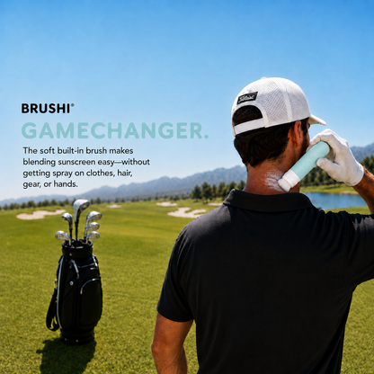 A man on a golf course wearing a white cap and white glove applies sunscreen from a BRUSHI sunscreen applicator Gamechanger bottle to his neck. A black golf bag with clubs is visible in the background under a clear blue sky.